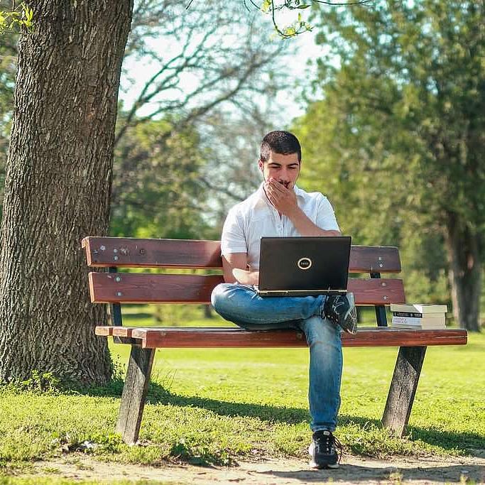 Mann mit Laptop auf einer Bank