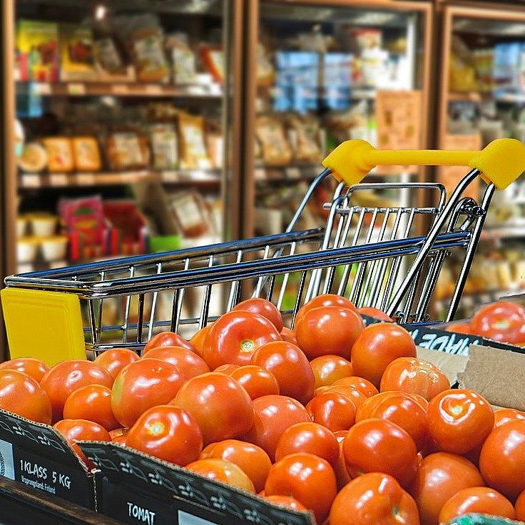 Im Supermarkt: Einkaufswagen hinter Tomatenstapel