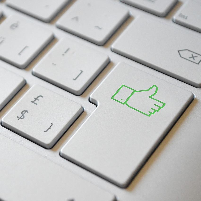 eine grüne Daumen-Hoch-Taste auf der Computertastatur